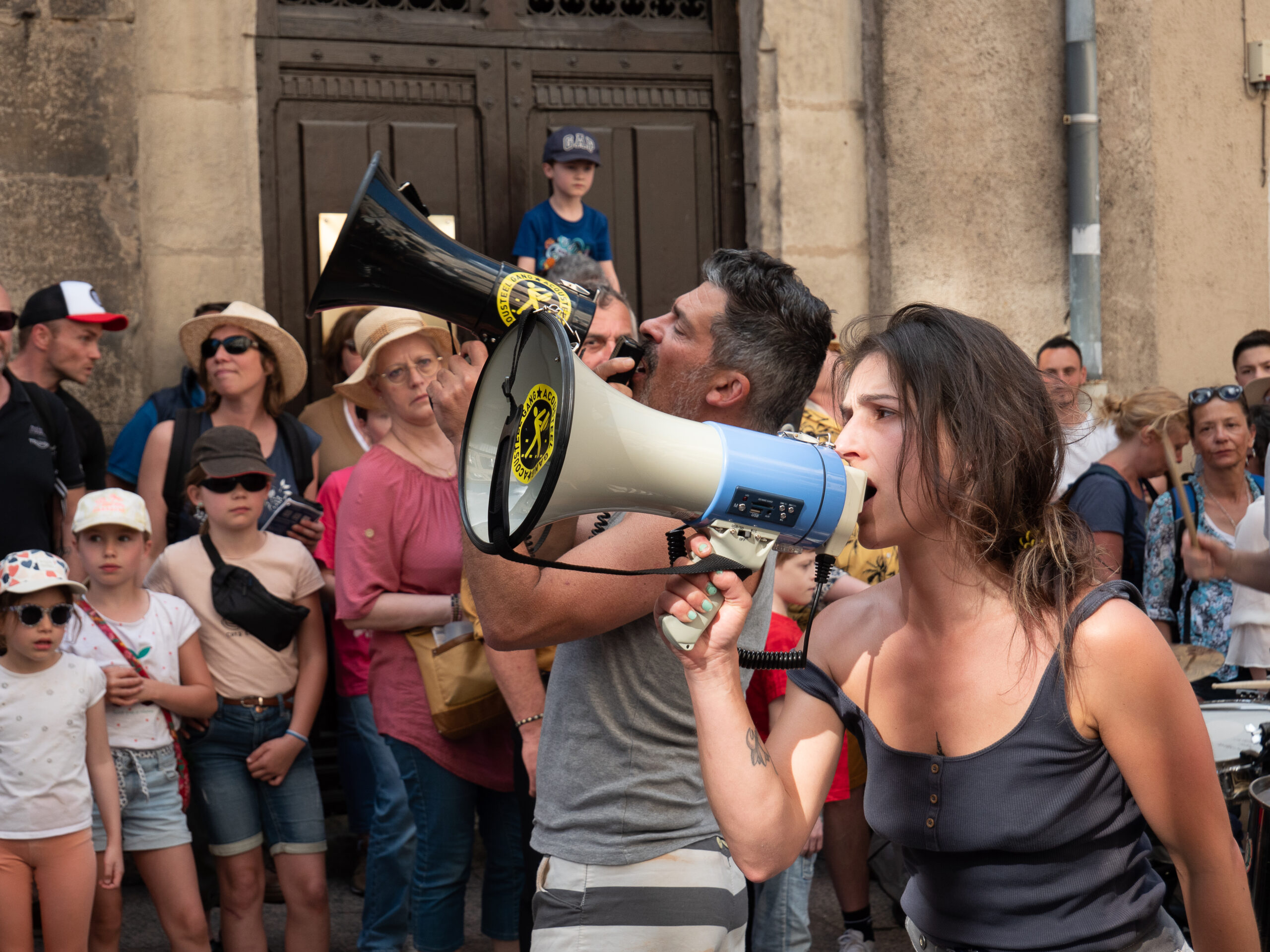un homme et une femme de la précédent troupe parlent dans deux mégaphone au milieu de la foule
