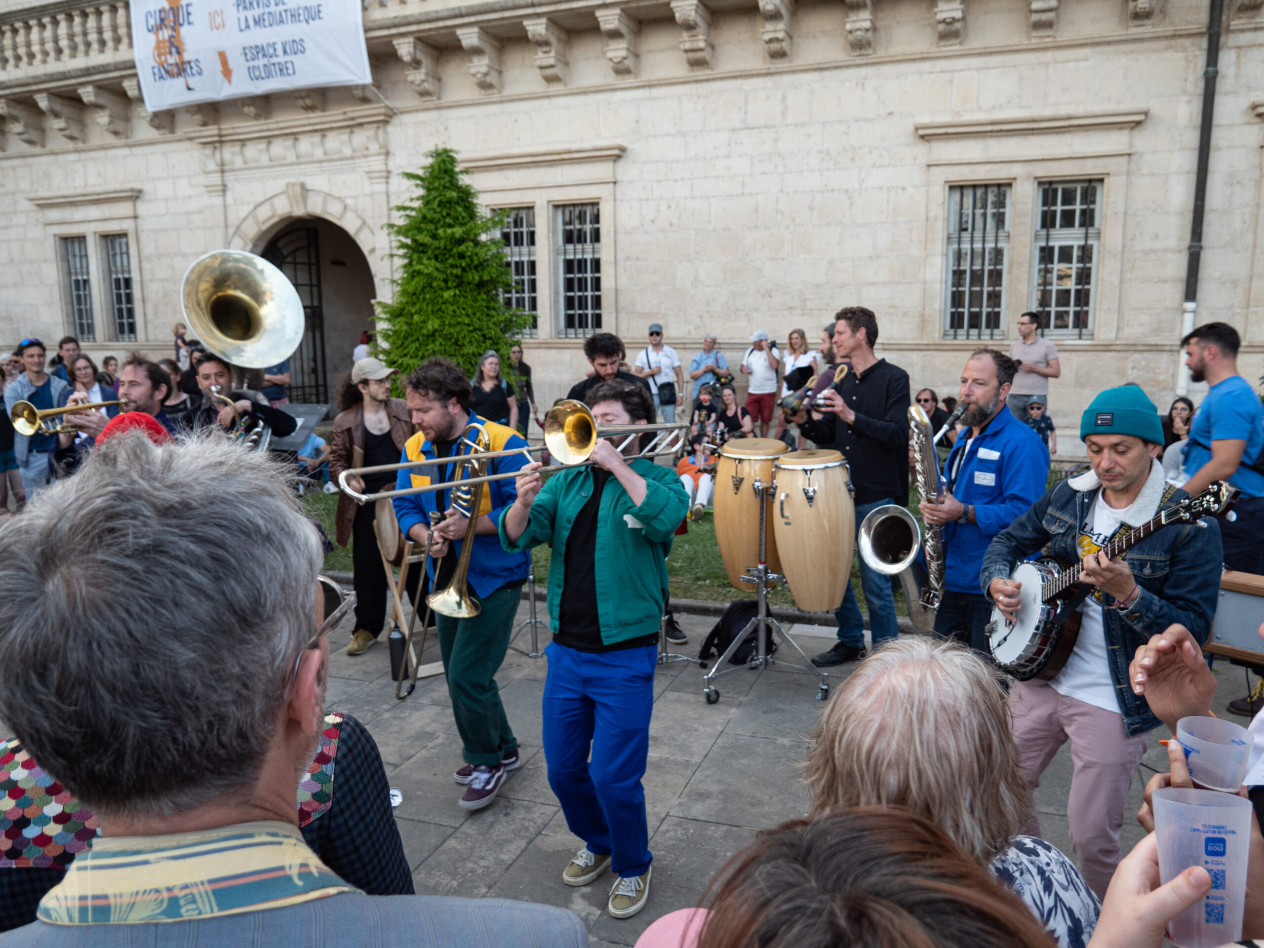 Formation musicale dans laquelle on aperçoit deux trombones, un conga, un tuba, une trompette, un saxophone basse et un banjo