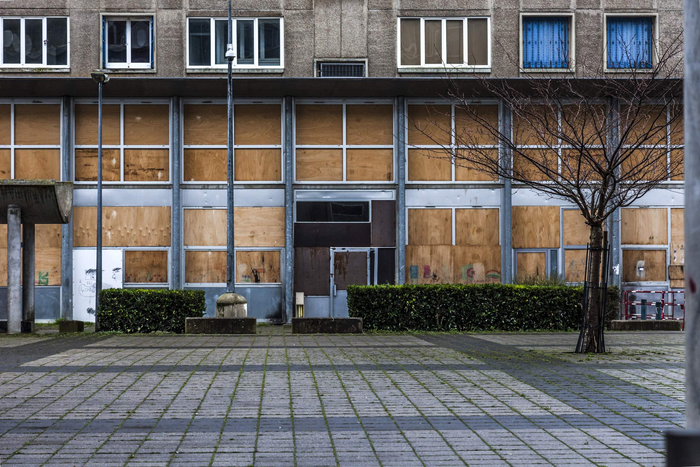 Détail d'une entrée d'un des immeubles des 408. Les fenêtres sont murées avec de panneaux de bois