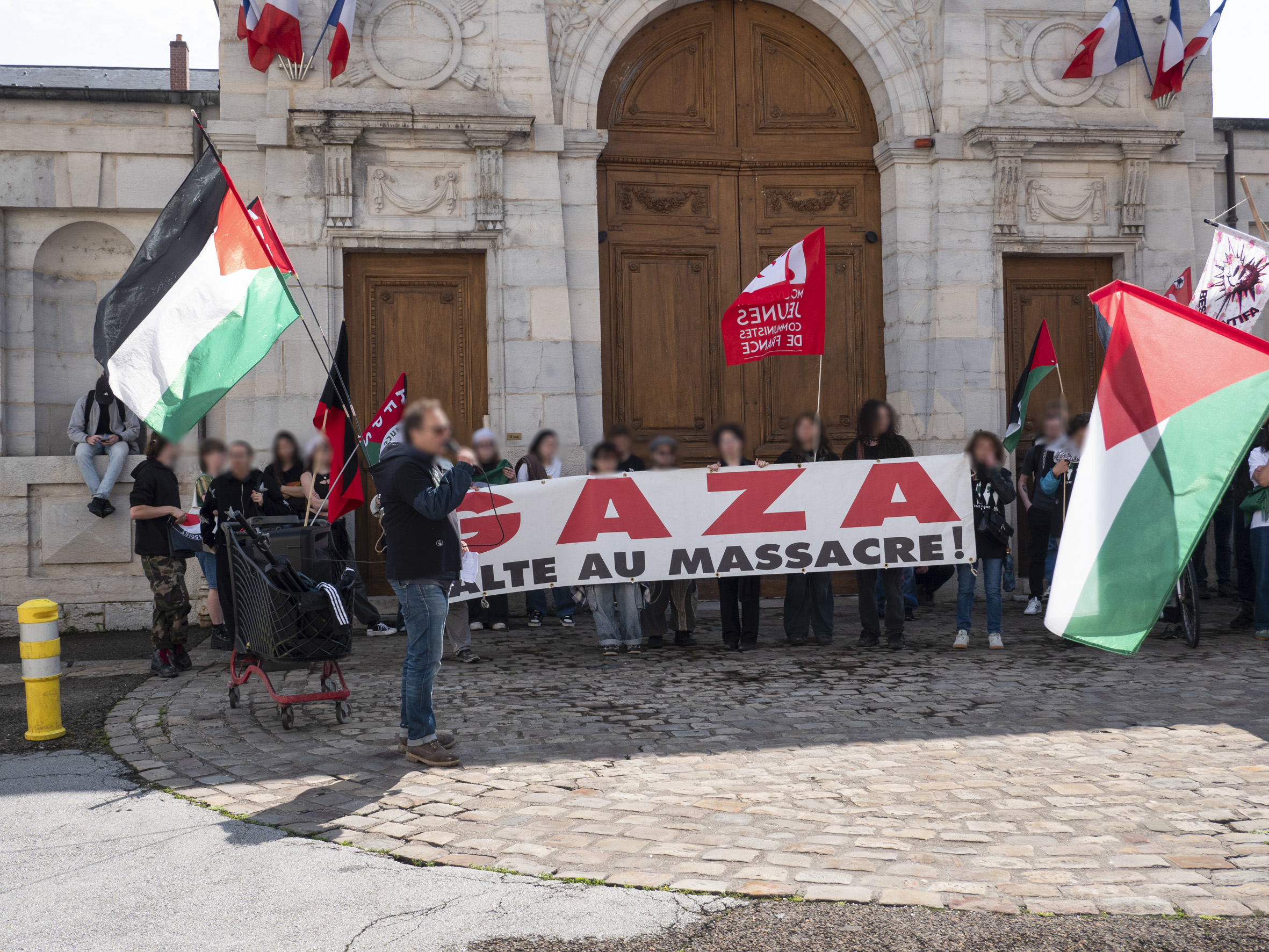 La pancarte Gaza, halte au massacre, déployée devant la porte de la préfecture, avec des drapeaux palestiniens