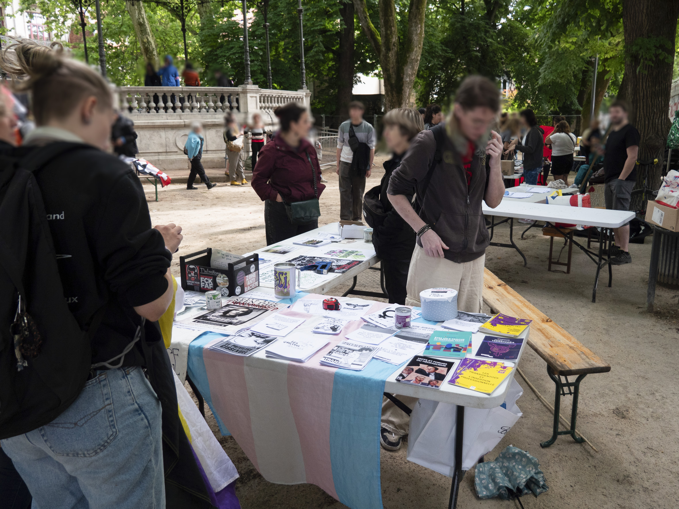 Vue d'un stand place Granvelle à Besançon, il présente des goodies disposés sur un drapeau trans