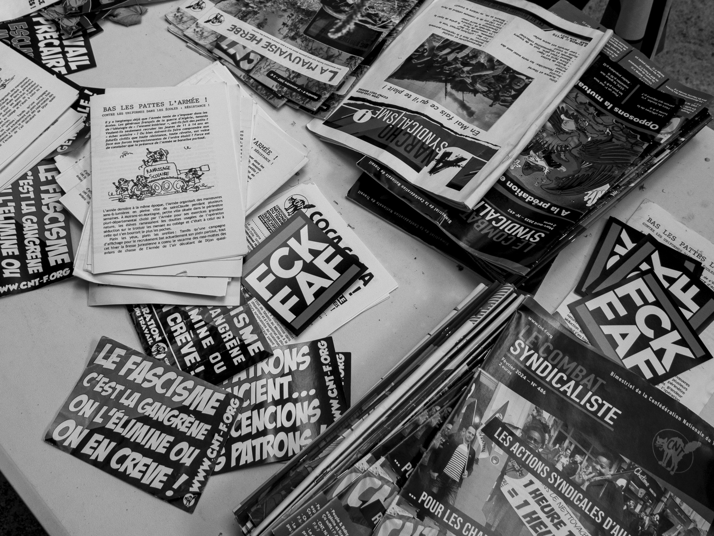 table sur laquelle on retrouve plusieurs stickers et des revues de la CNT