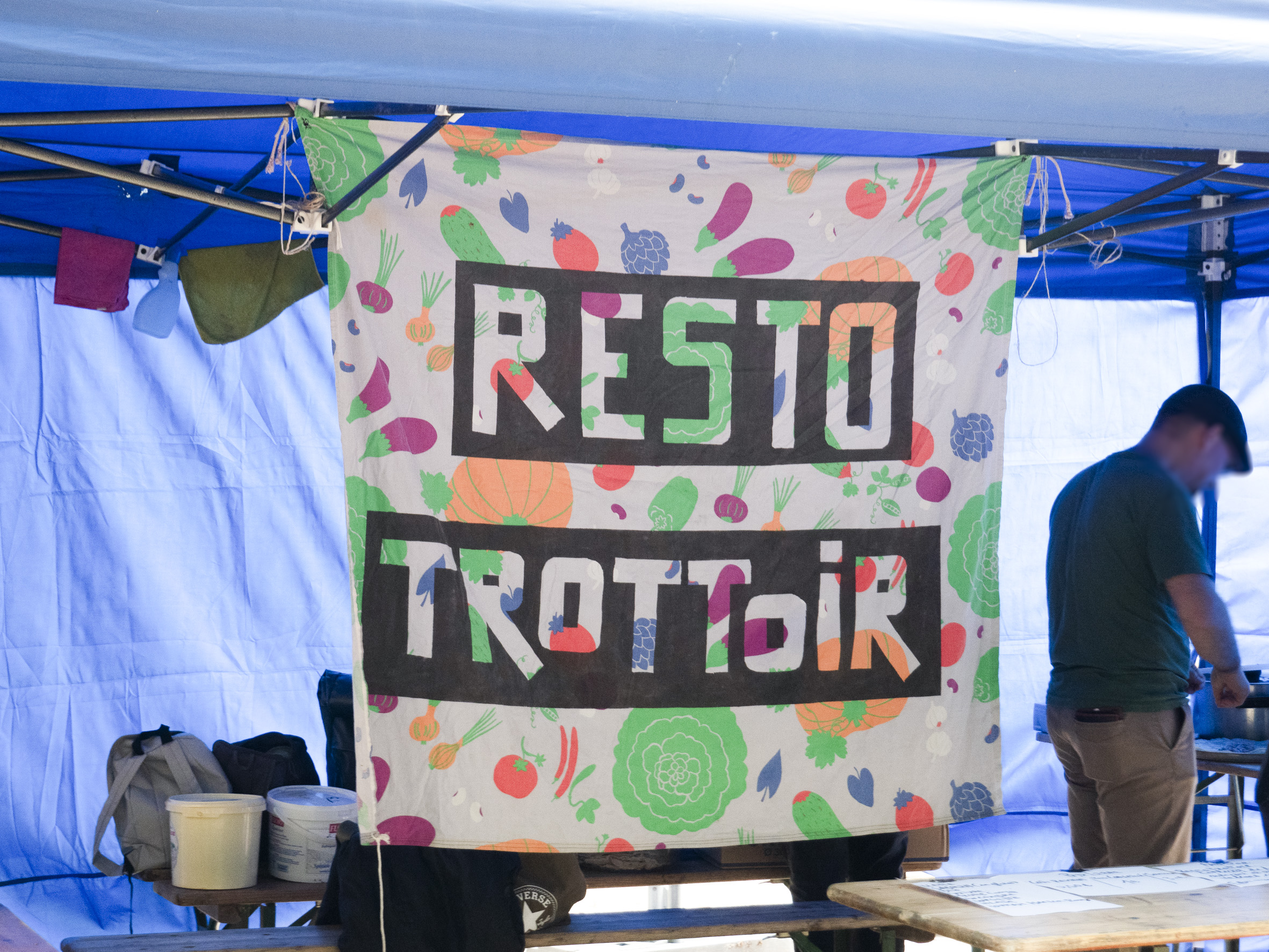 le stand du resto trottoir, avec sa banderole faite d'images de légumes stylisés et colorés