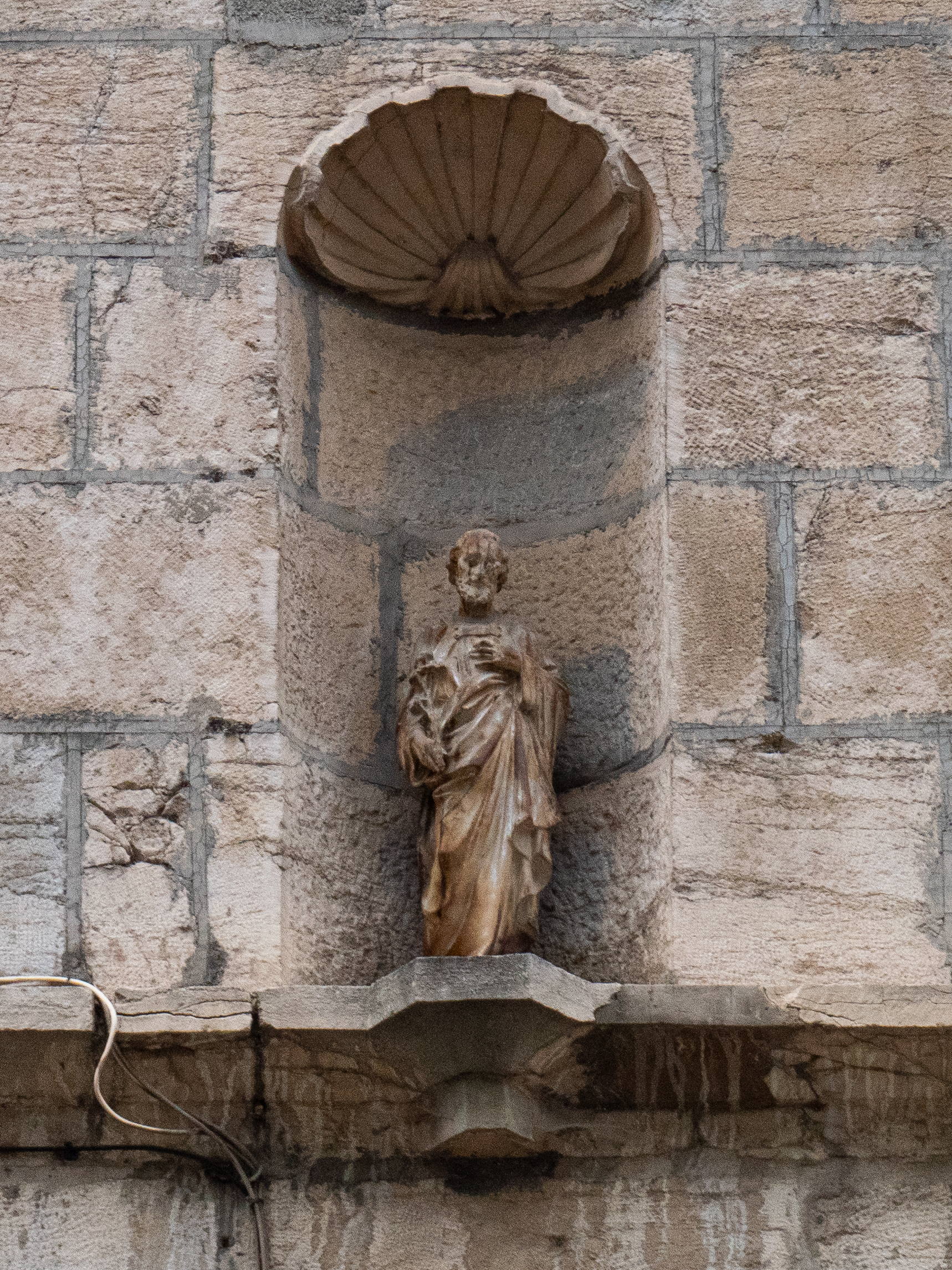 sculpture en pierre d'un saint dans une alcôve, surmontée d'un genre de plafond en coquillage