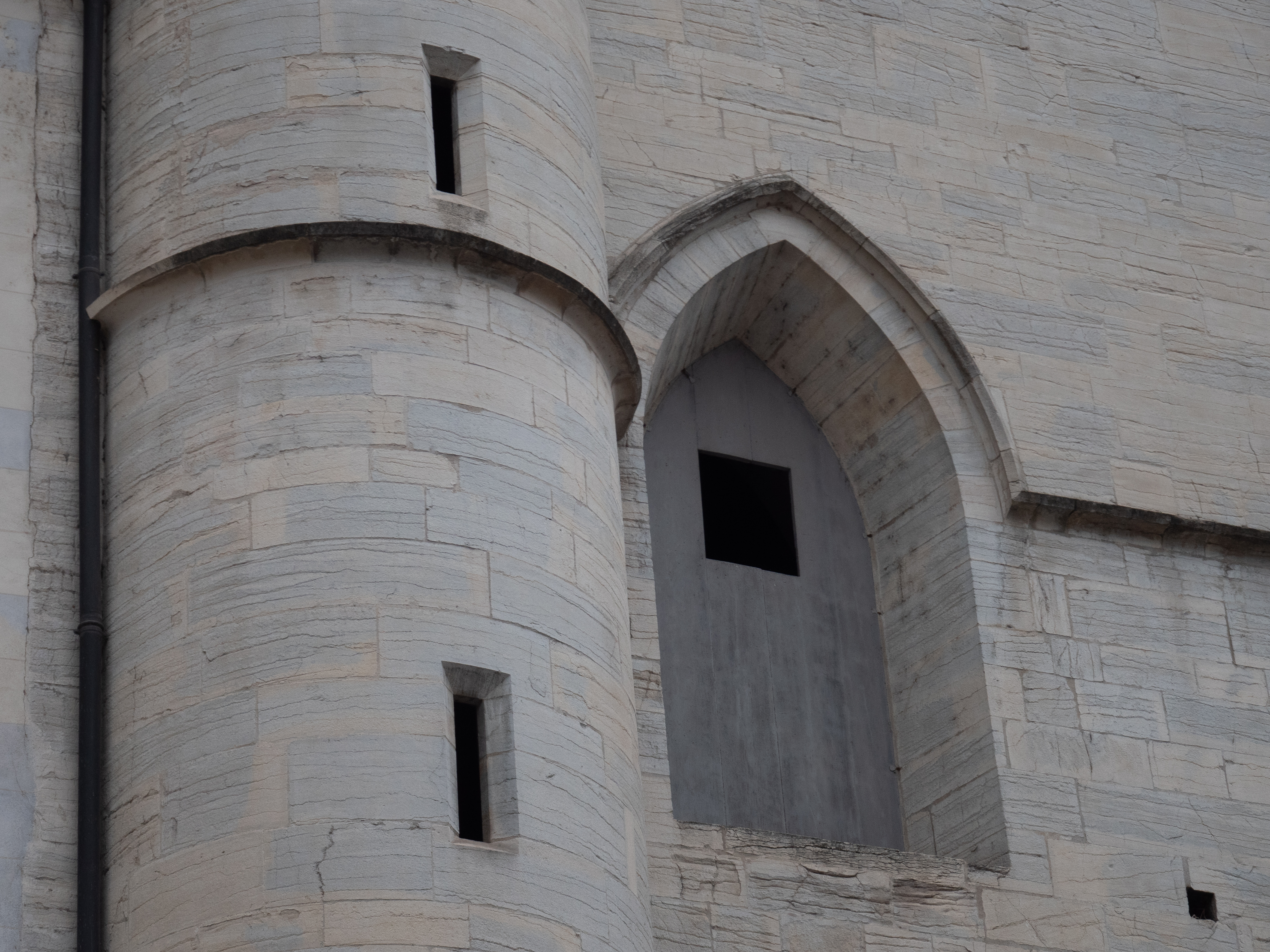 porte en bois dans une ouverture en pierre avec une voute d'ogive, à côté d'une tour ronde à meurtrières