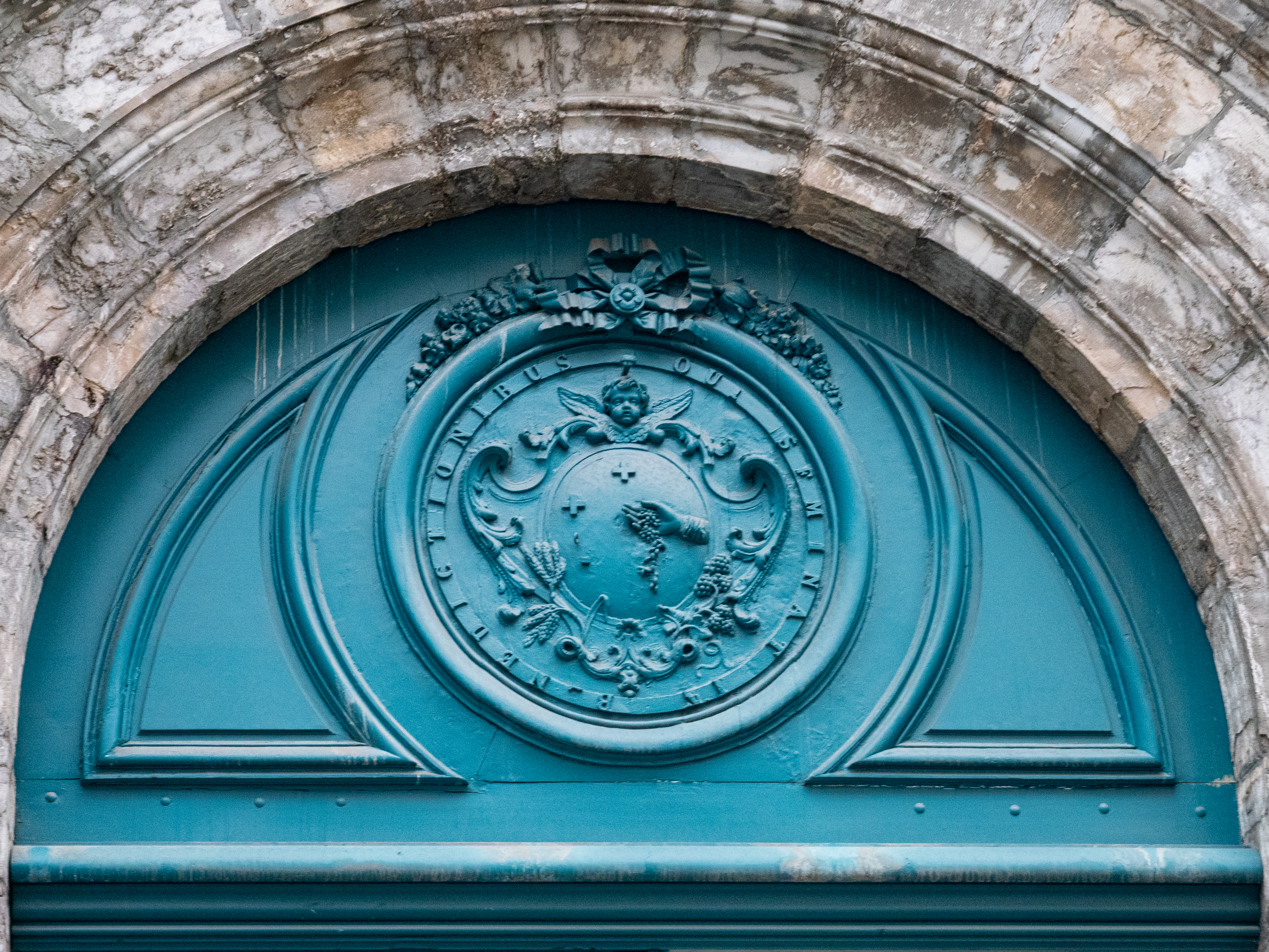 fronton de porte cochère en bois bleu, représentant un ange au-dessus d'une sphère dans laquelle une main semble semer des graines