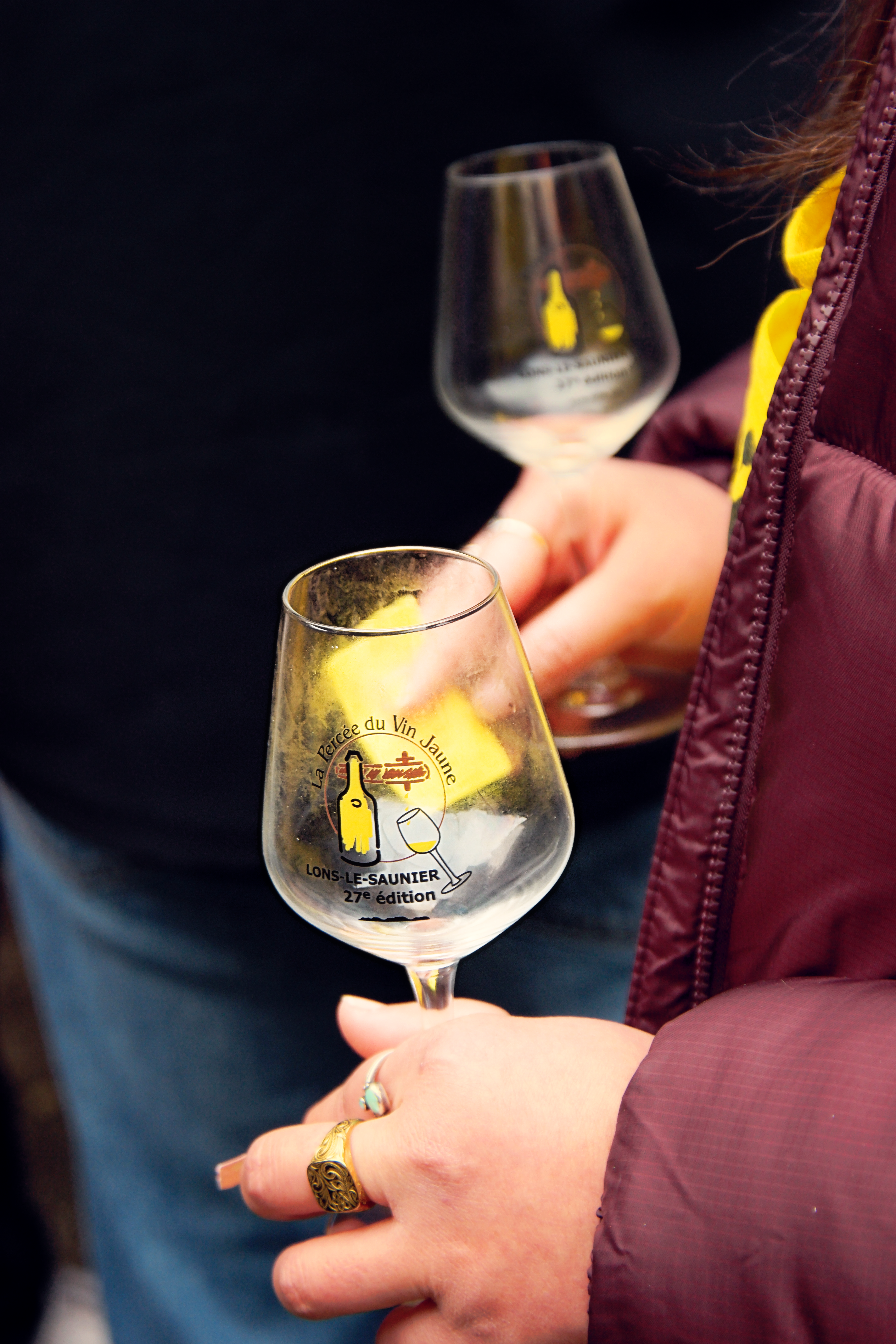 gros plan de deux mains tenant deux verres de vin jaune