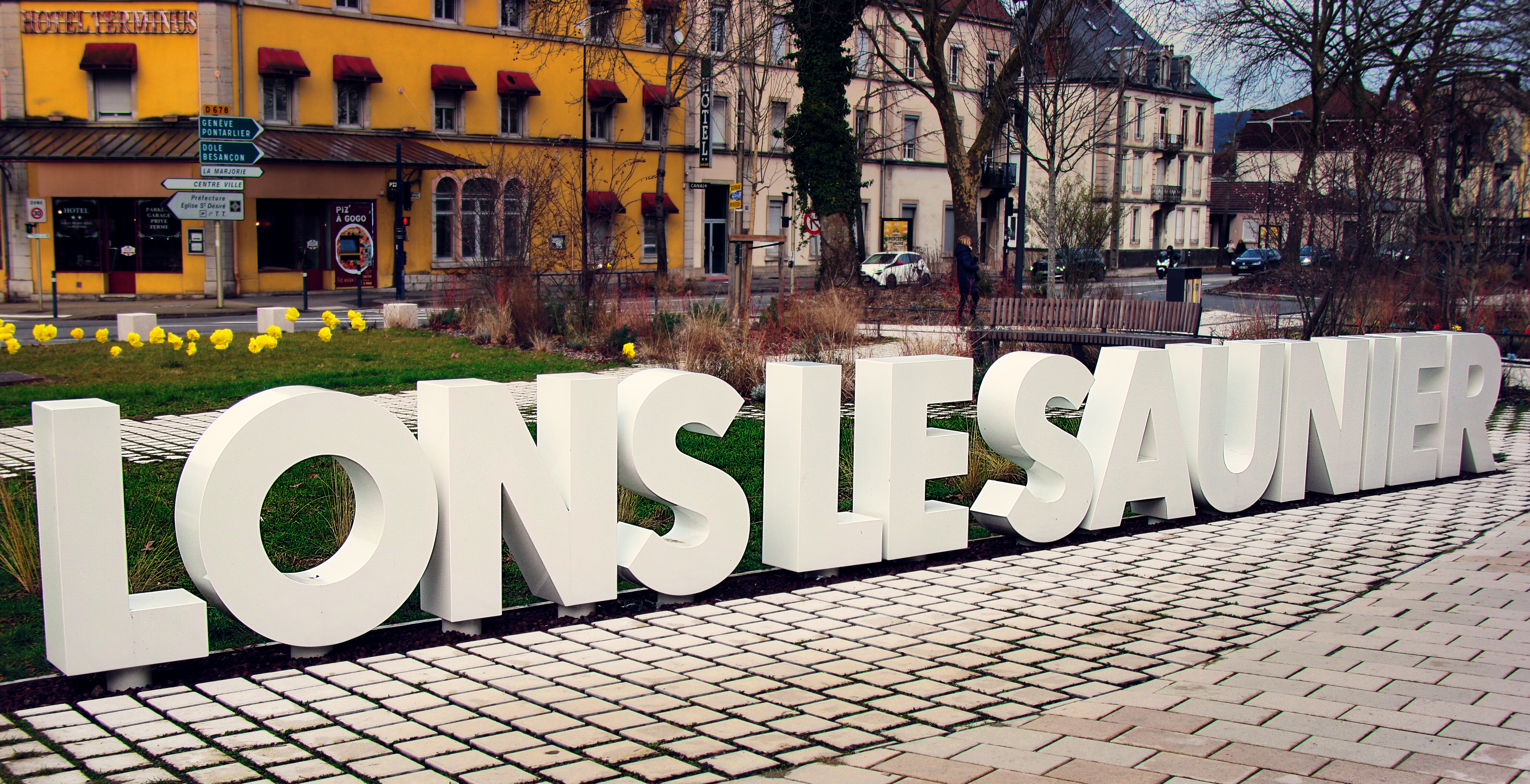 Lons le Saunier écrit en grosses lettres 3D en plastique blanc sur le parking de la gare