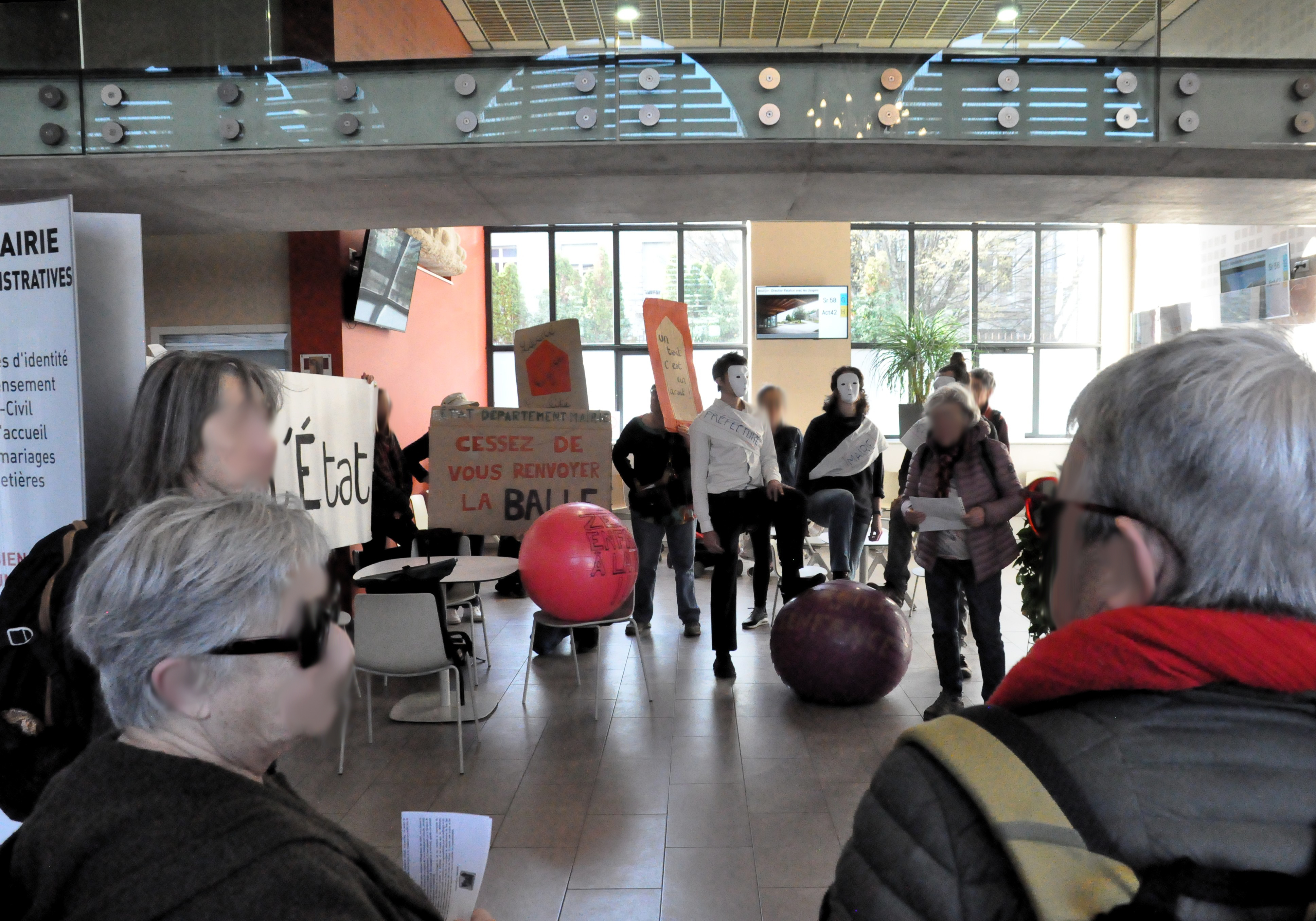 Les trois personnes masquées en blanc posent à nouveau le pied sur le ballon de gymnastique "droits de l'enfance", avec la pancarte "état, département, mairie, cessez de vous renvoyer la balle", cette fois dans la mairie. Une autre personne tient une pancarte "liberté, égalité, enfance" juste derrière.