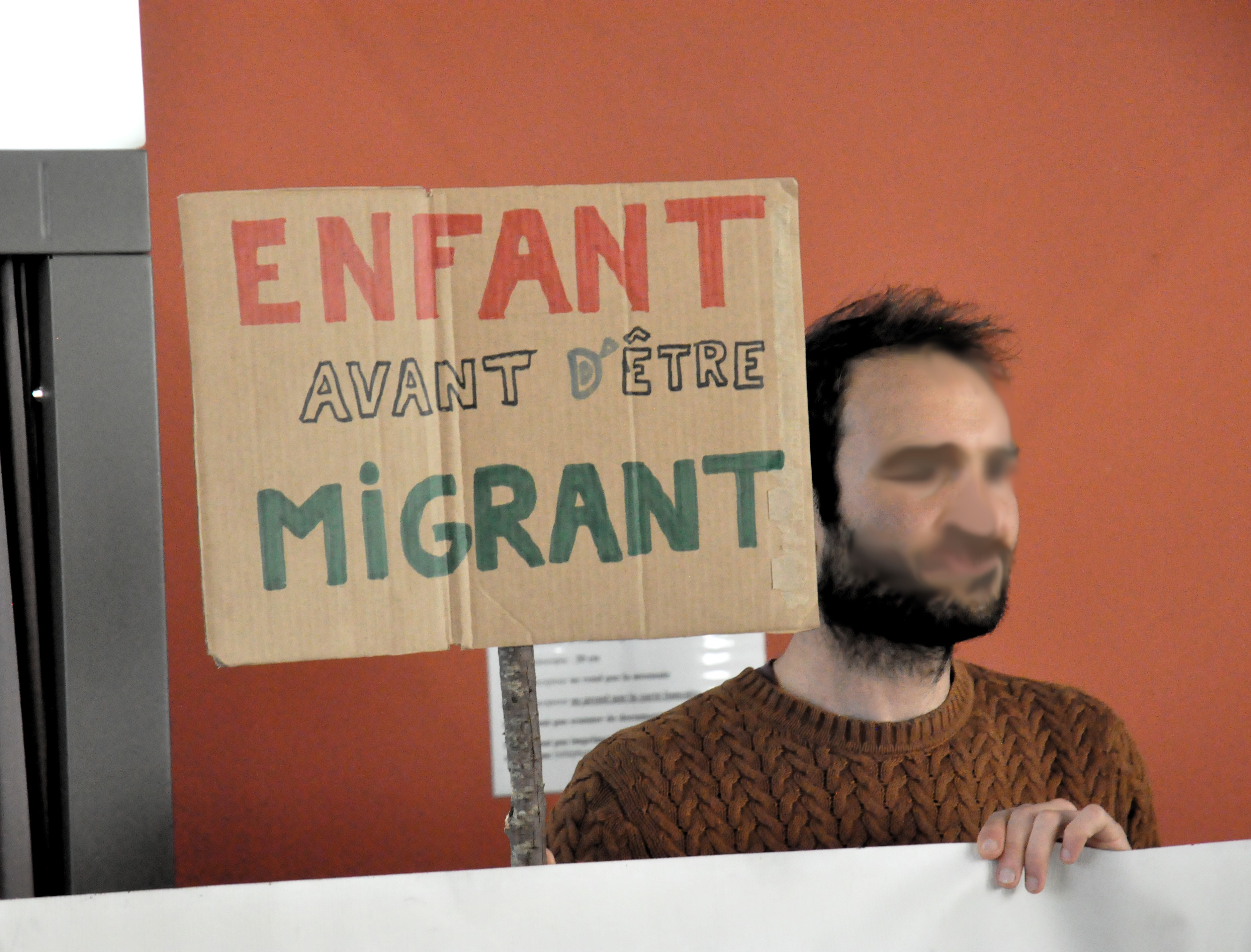 Une personne tient une pancarte "enfant avant d'être migrant".