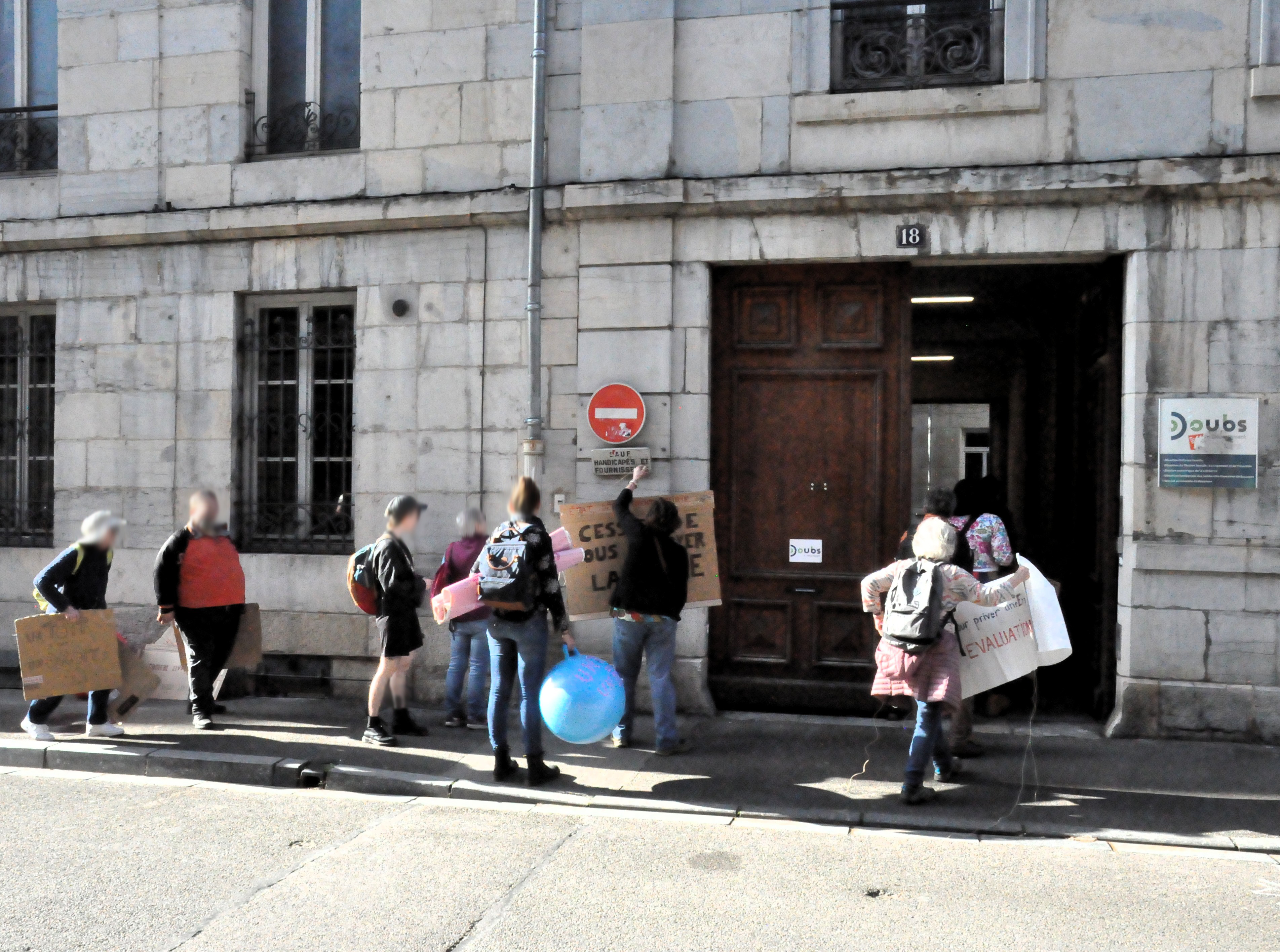 Le groupe de personnes rentre avec ses pancartes dans les locaux du département du Doubs