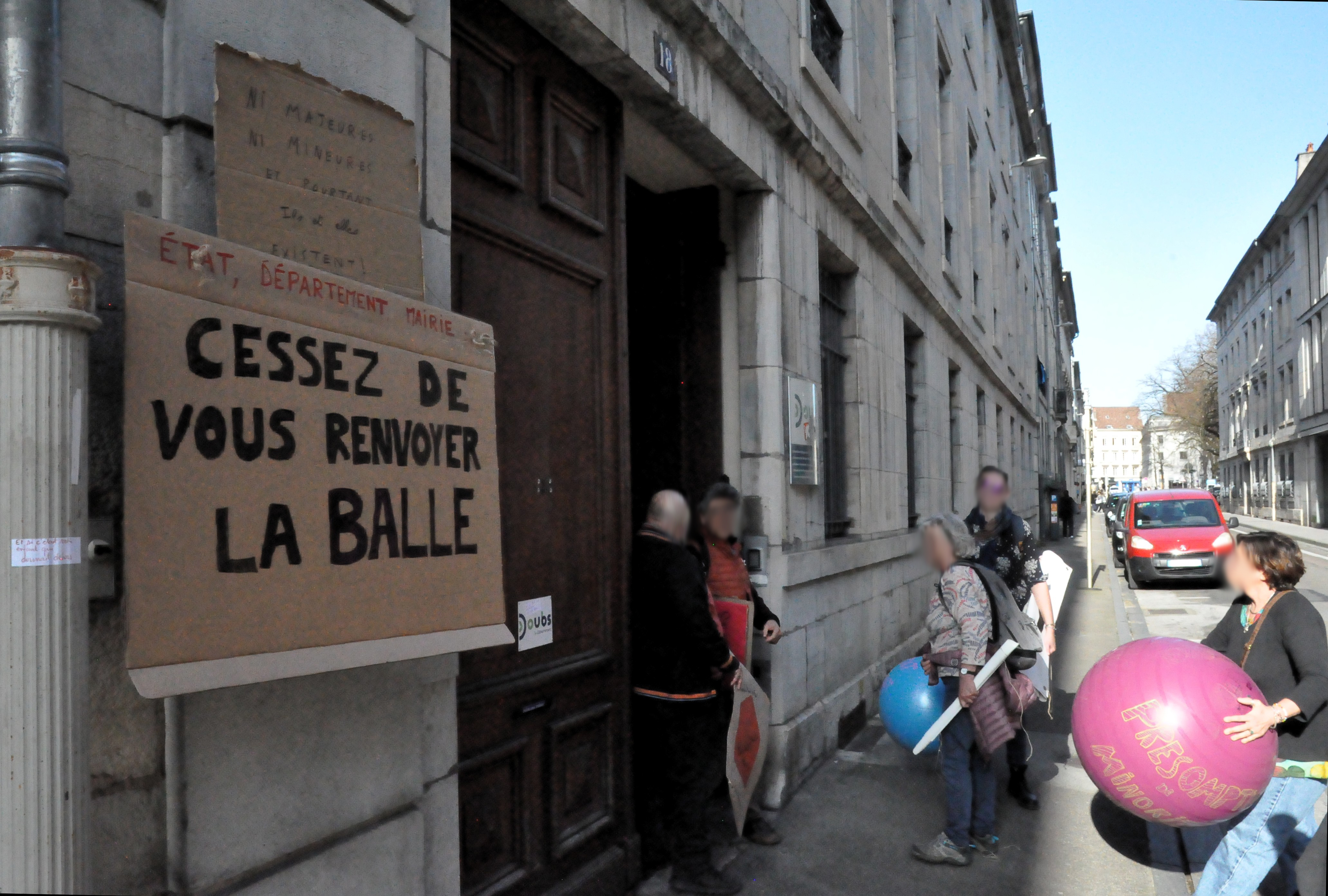le groupe de personnes à nouveau devant les locaux du département du Doubs, avec la pancarte "état, département, mairie, cessez de vous renvoyer la balle" bien en évidence