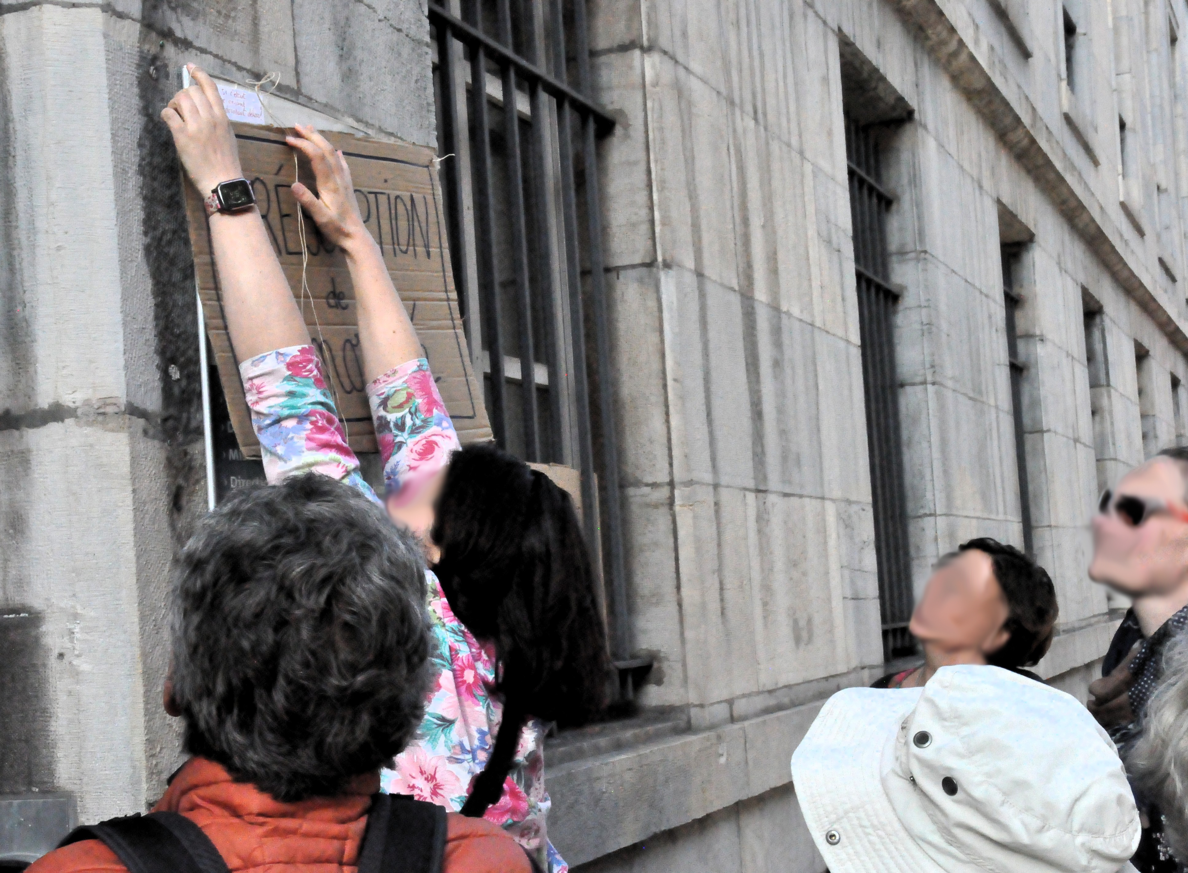 Personne en train d'accrocher une pancarte "présomption de minorité" sur un mur