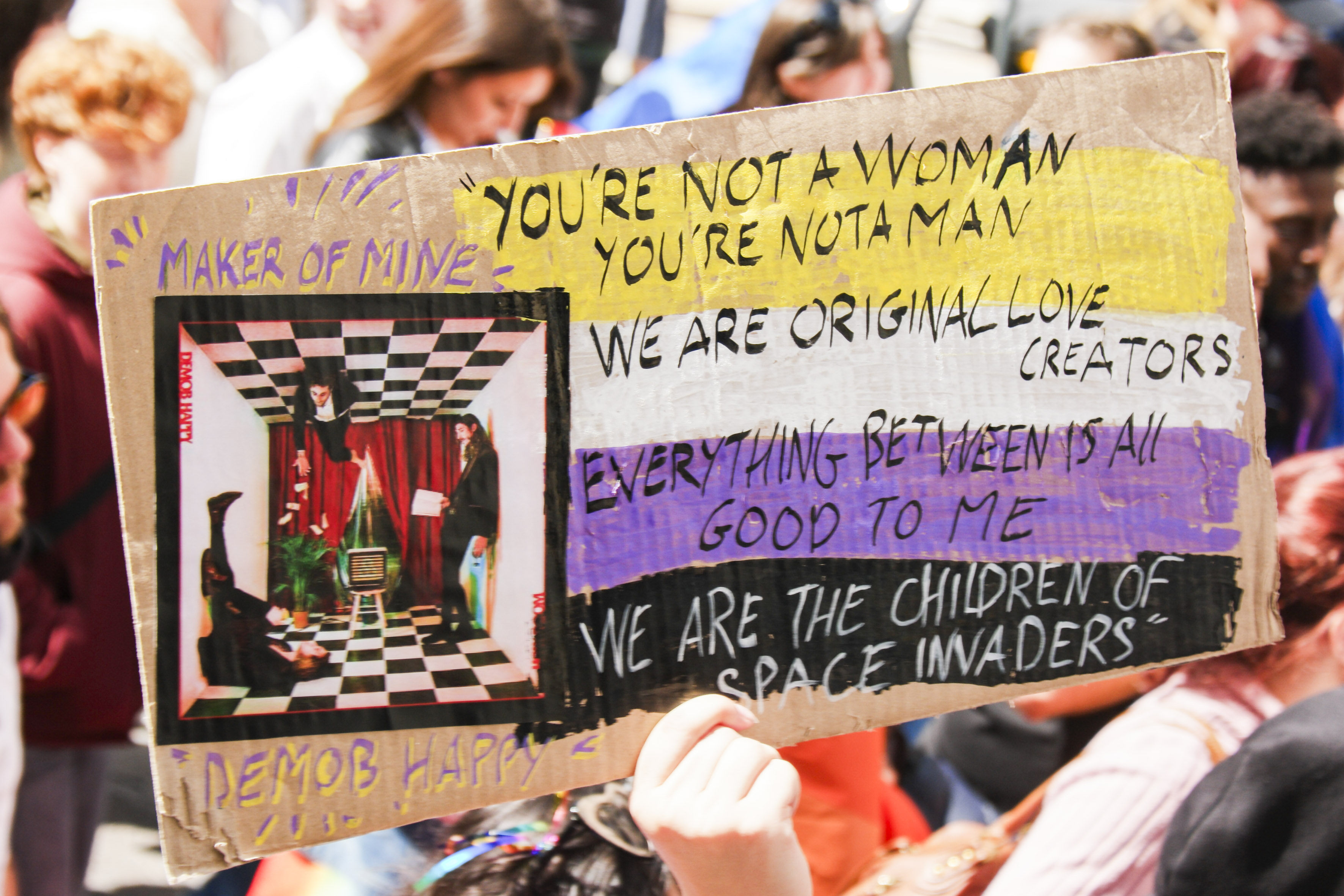 Pancarte : you're not a woman, you're not a man, we are original love creators, everything between is all good to me, we are the children of space invaders