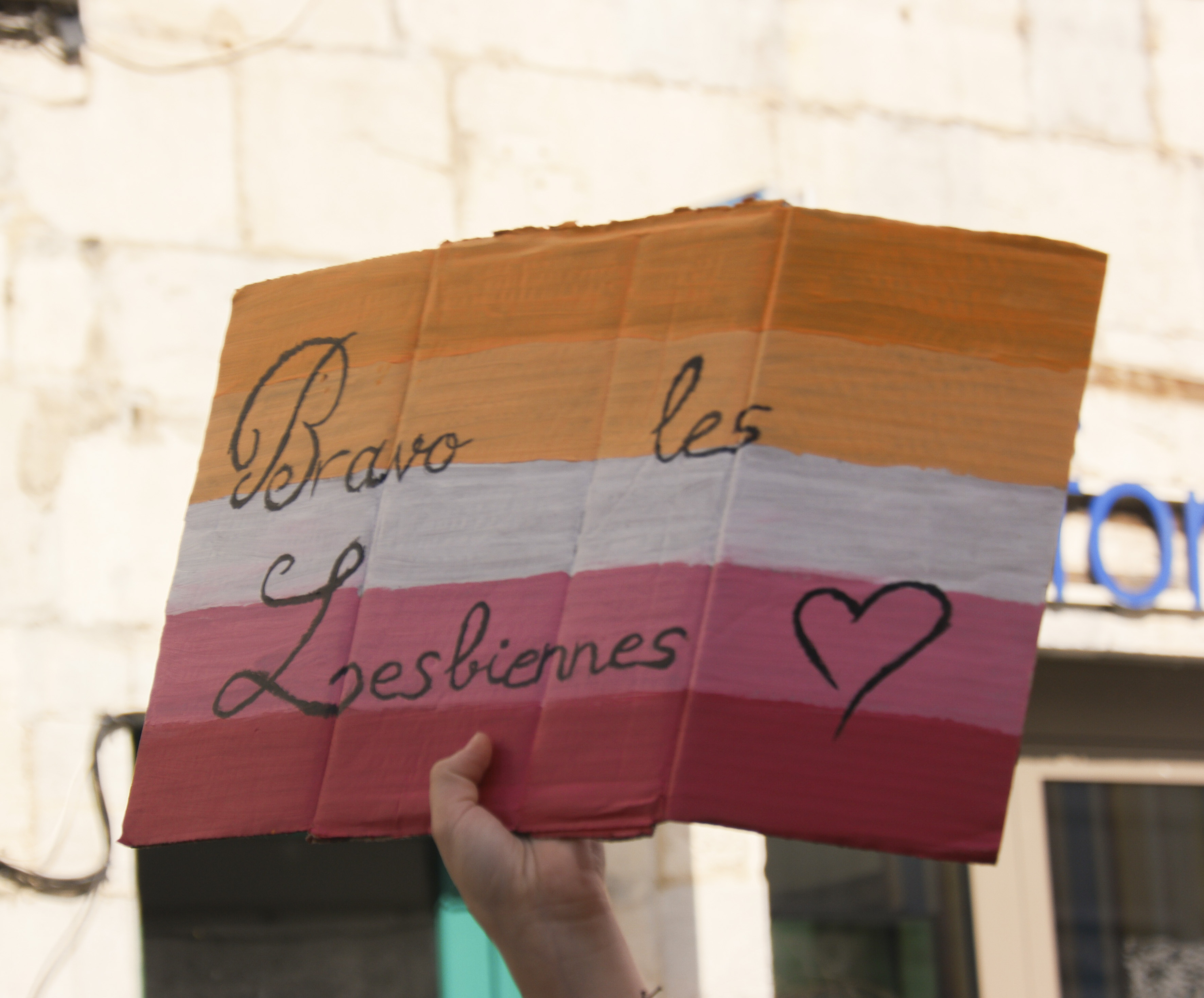 Une pancarte bravo les lesbiennes au couleurs de la fierté lesbienne