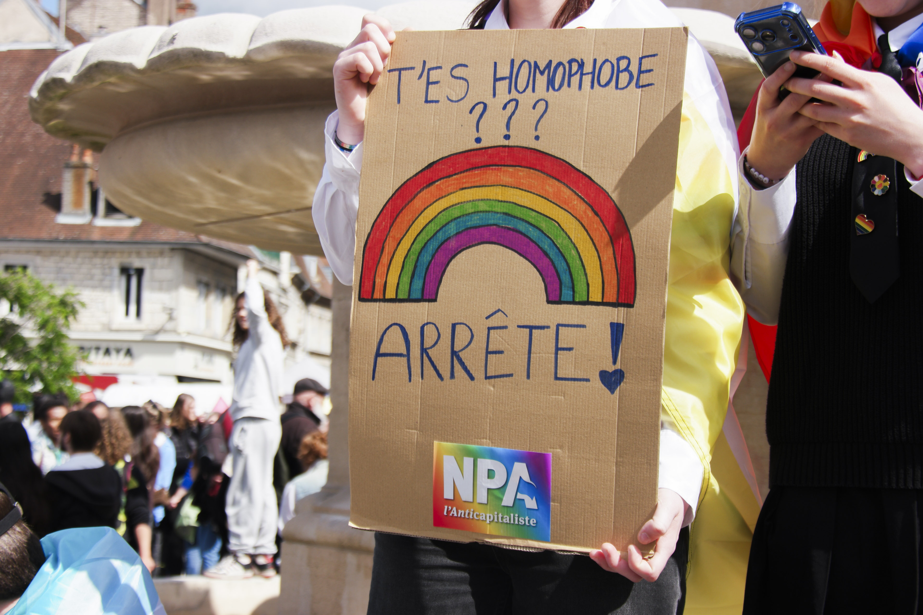 Une pancarte avec un sticker du NPA, avec l'inscription T'es homophobe ? Arrête !