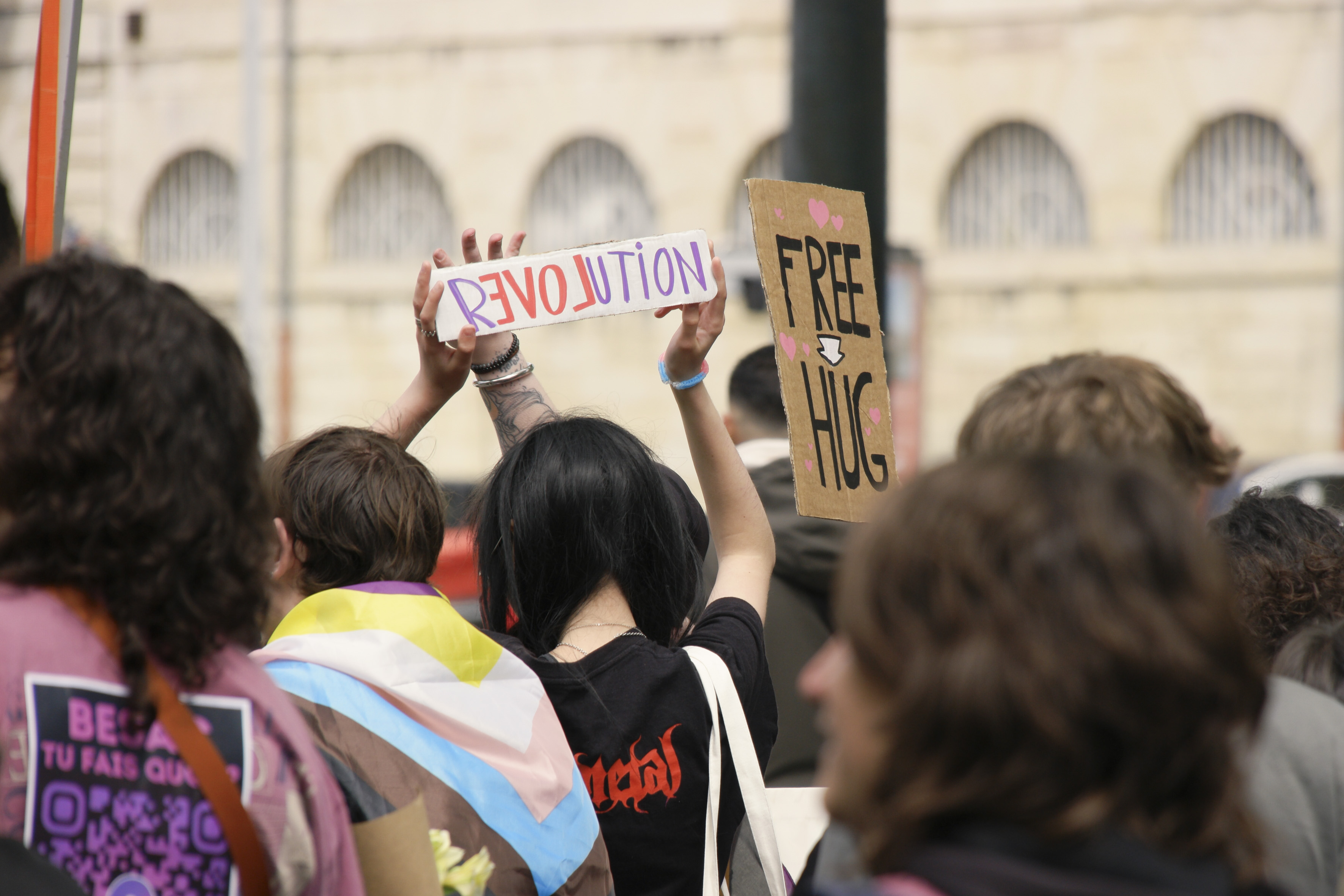 Un écriteau RéLOVEution à côté d'une pancarte Free Hugs