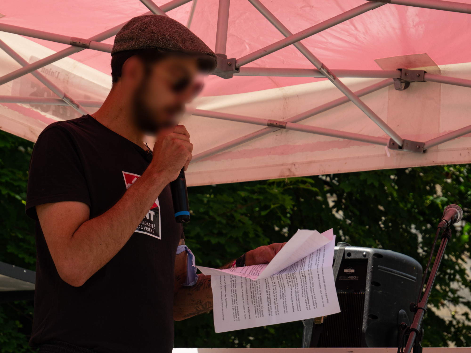 Prise de parole d'un militant sous un chapiteau. Il a un t-shirt CNT.