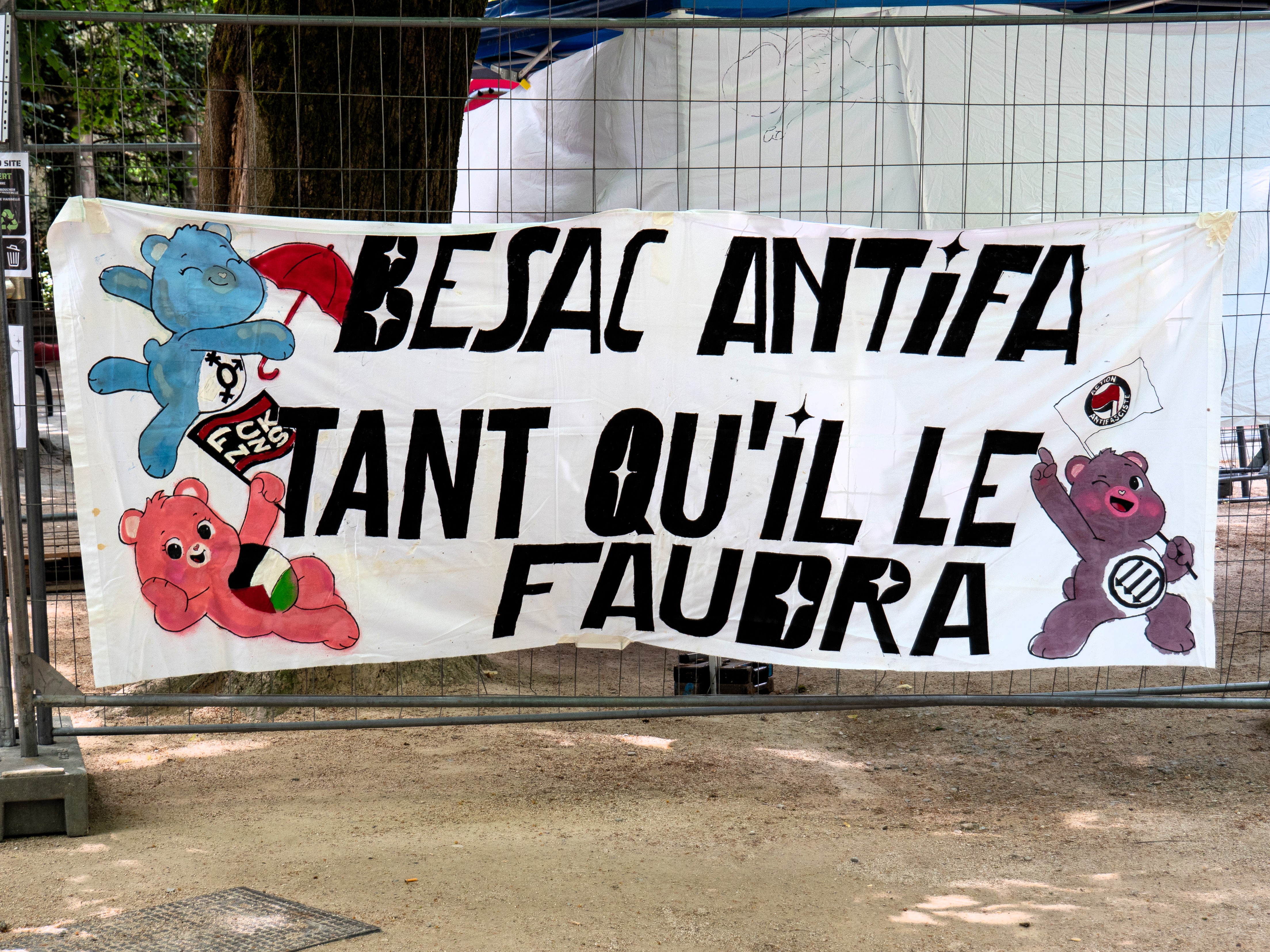 Banderole avec trois bisounours arborant des logos antifascistes, palestinien et queer, avec la mention Besac Antifa, tant qu'il le faudra. Les trois bisounours tiennent respectivement un parapluie rouge, un drapeau FCK NZS et une drapeau antifasciste
