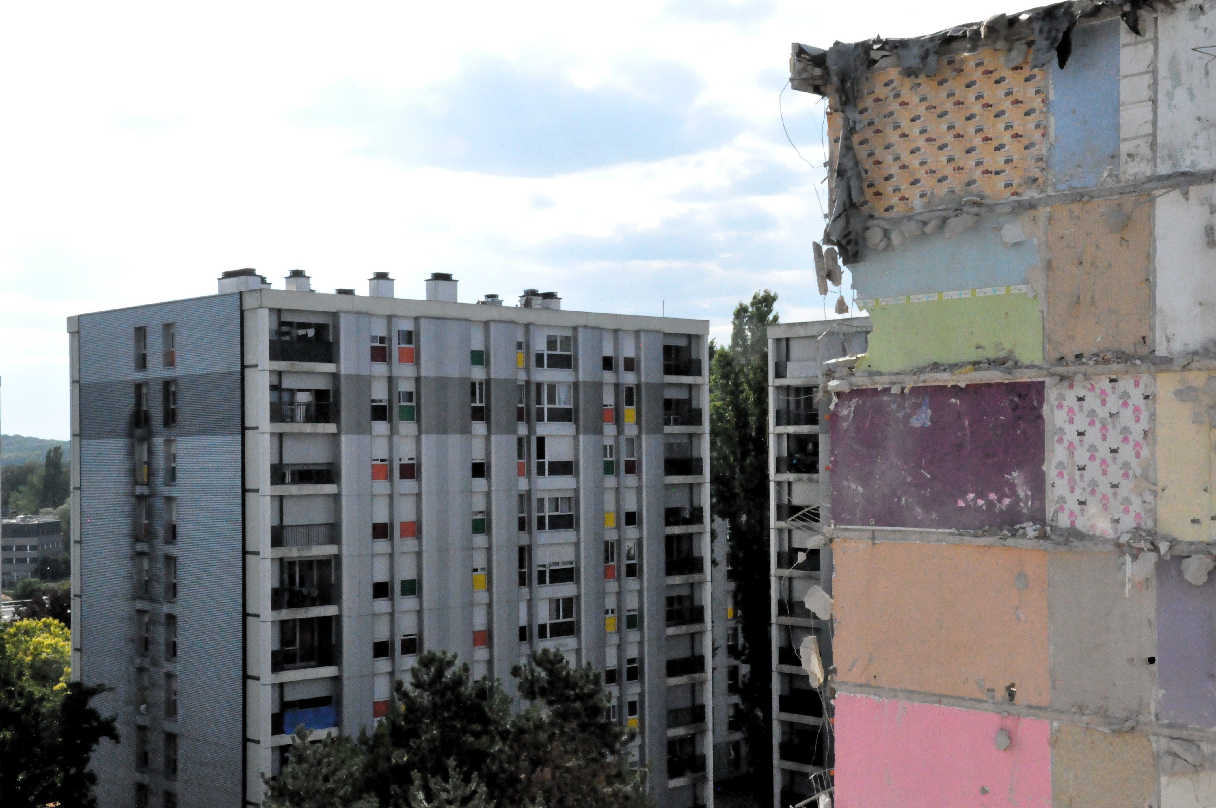 la vue à l'arrière plan d'un immeuble aux fenêtres colorées, avec à l'avant-plan un bout d'immeuble coloré totalement délabré