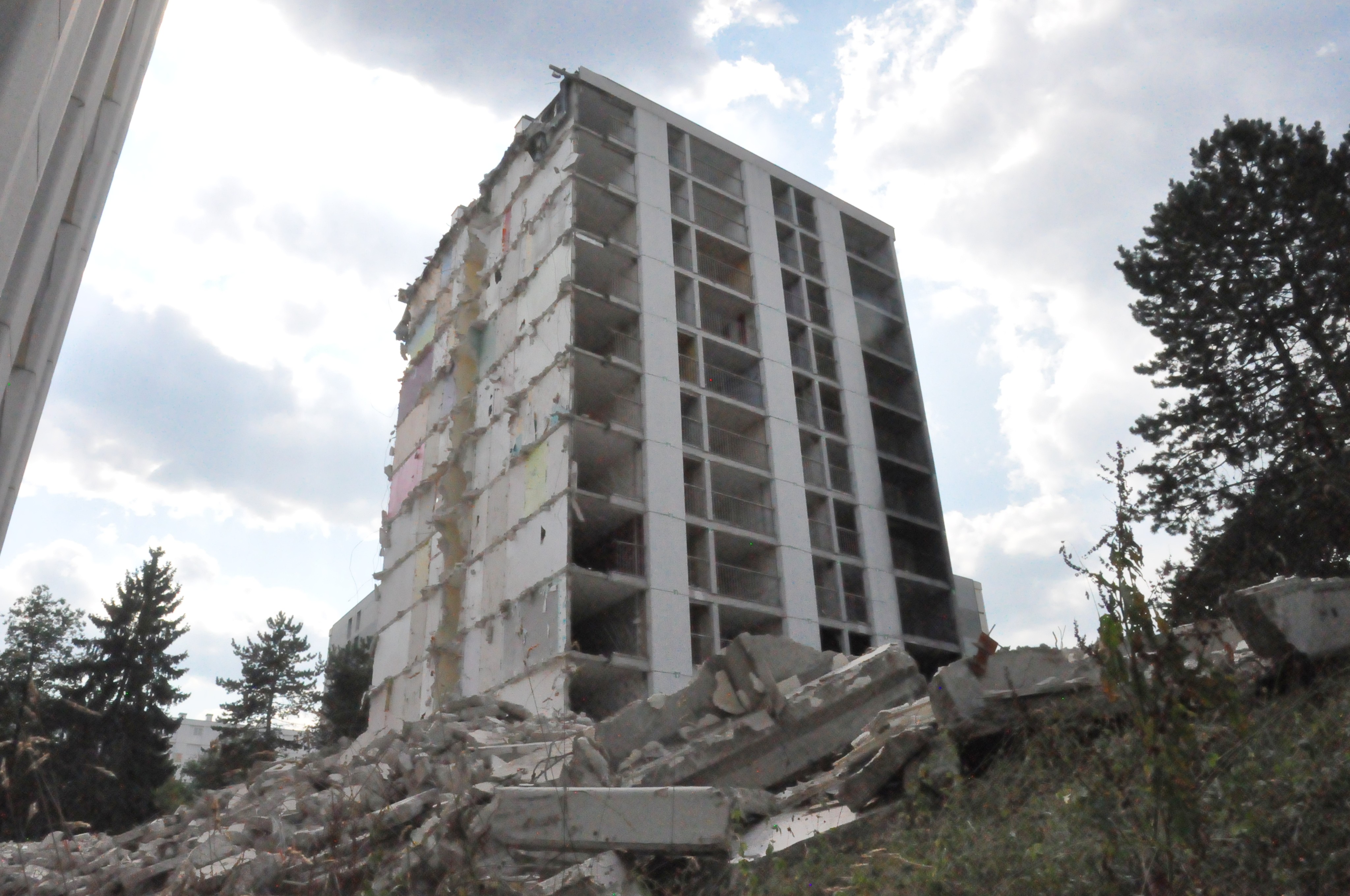 Vue en contre-plongée d'un immeuble à la façade arrachée, derrière un tas de gravats