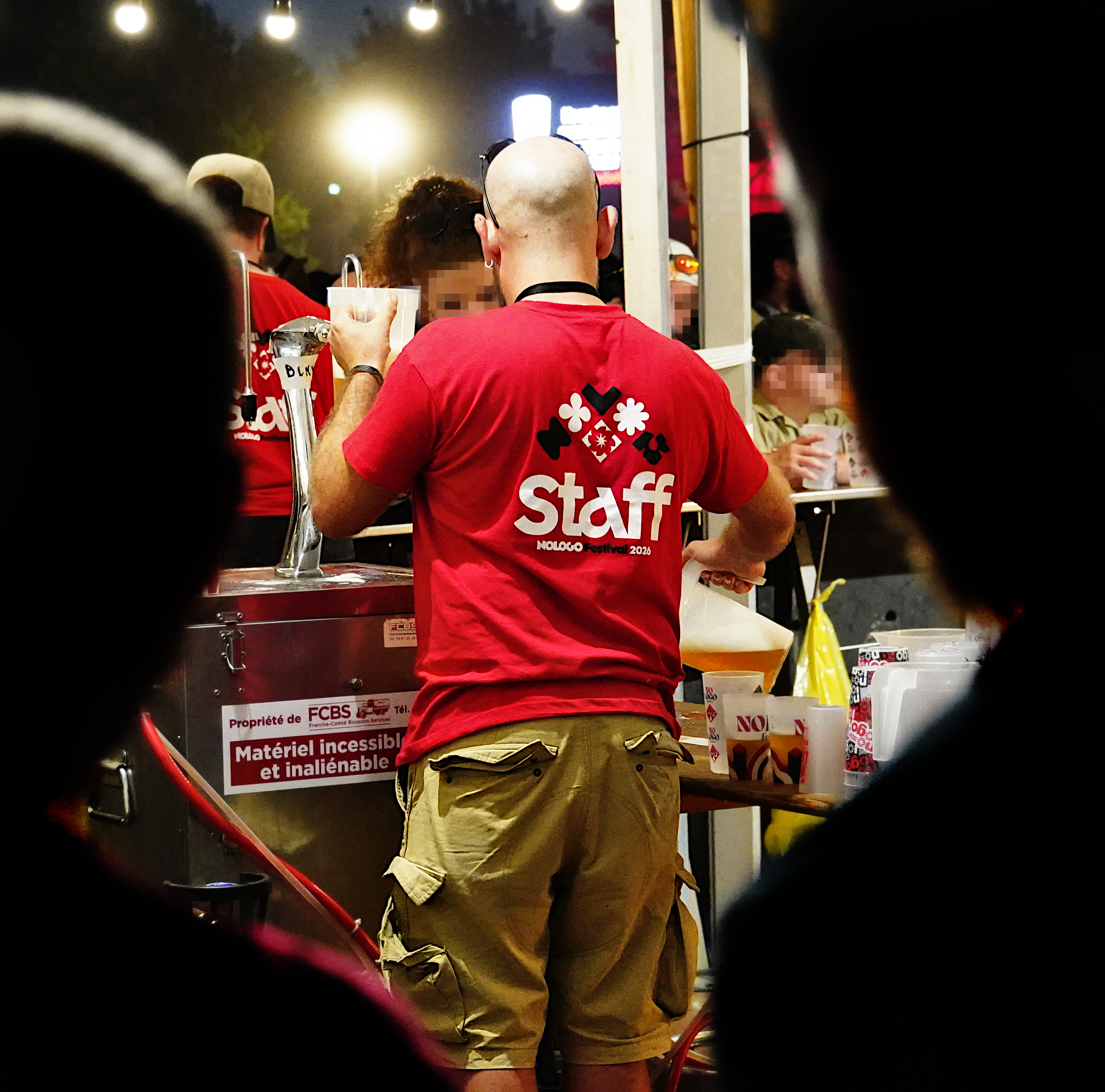 photo de dos d'une personne du staff en train de servir de la bière, au bar