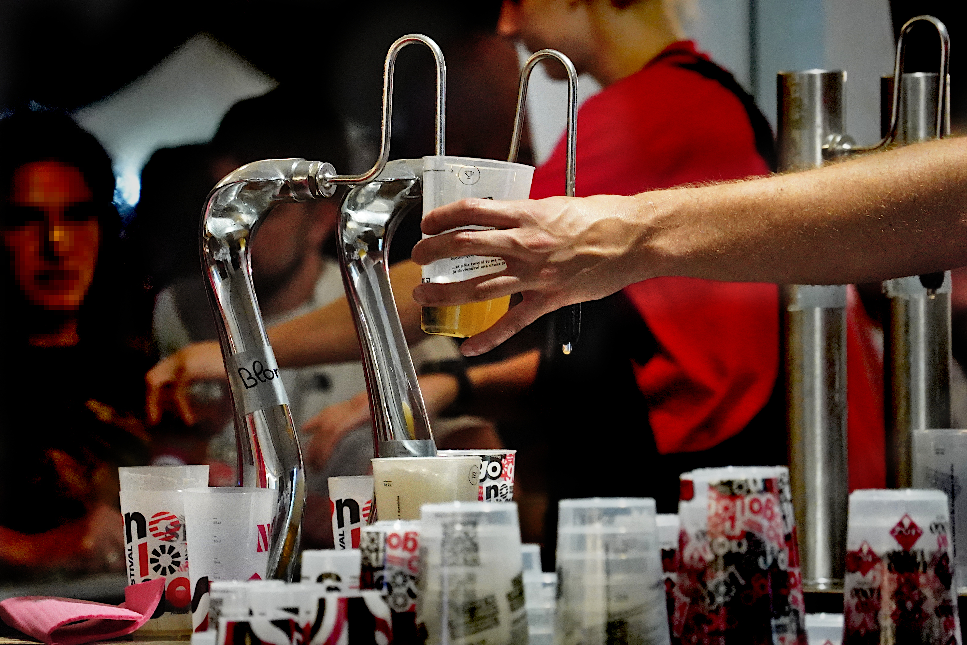 une bière en train d'être servie à la presse, au bar, dans des verres floqués No Logo, qu'on aperçoit par dizaines à l'avant-plan, retournés