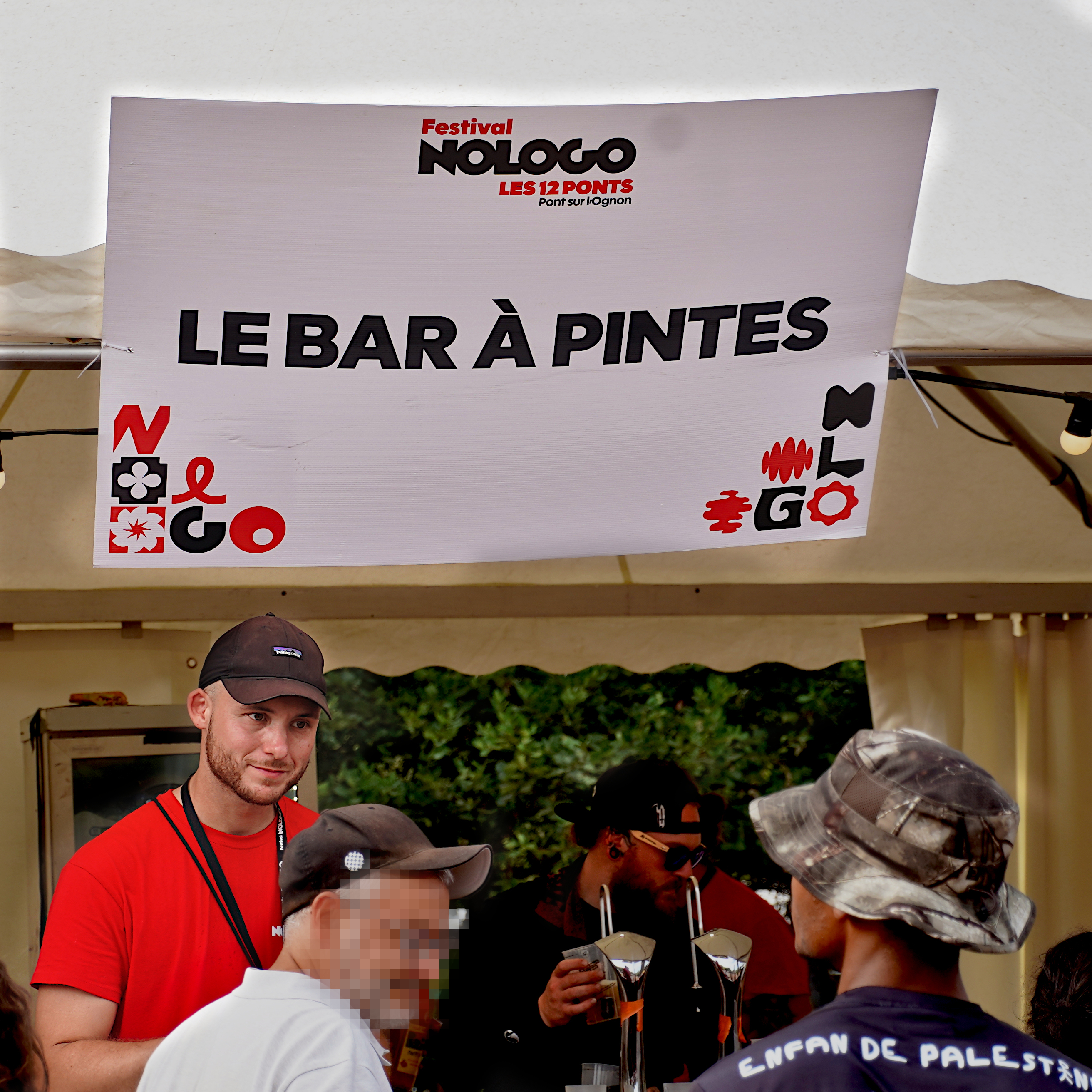 Public et staff sous la pancarte "le bar à pintes", annonçant un autre débit de boisson