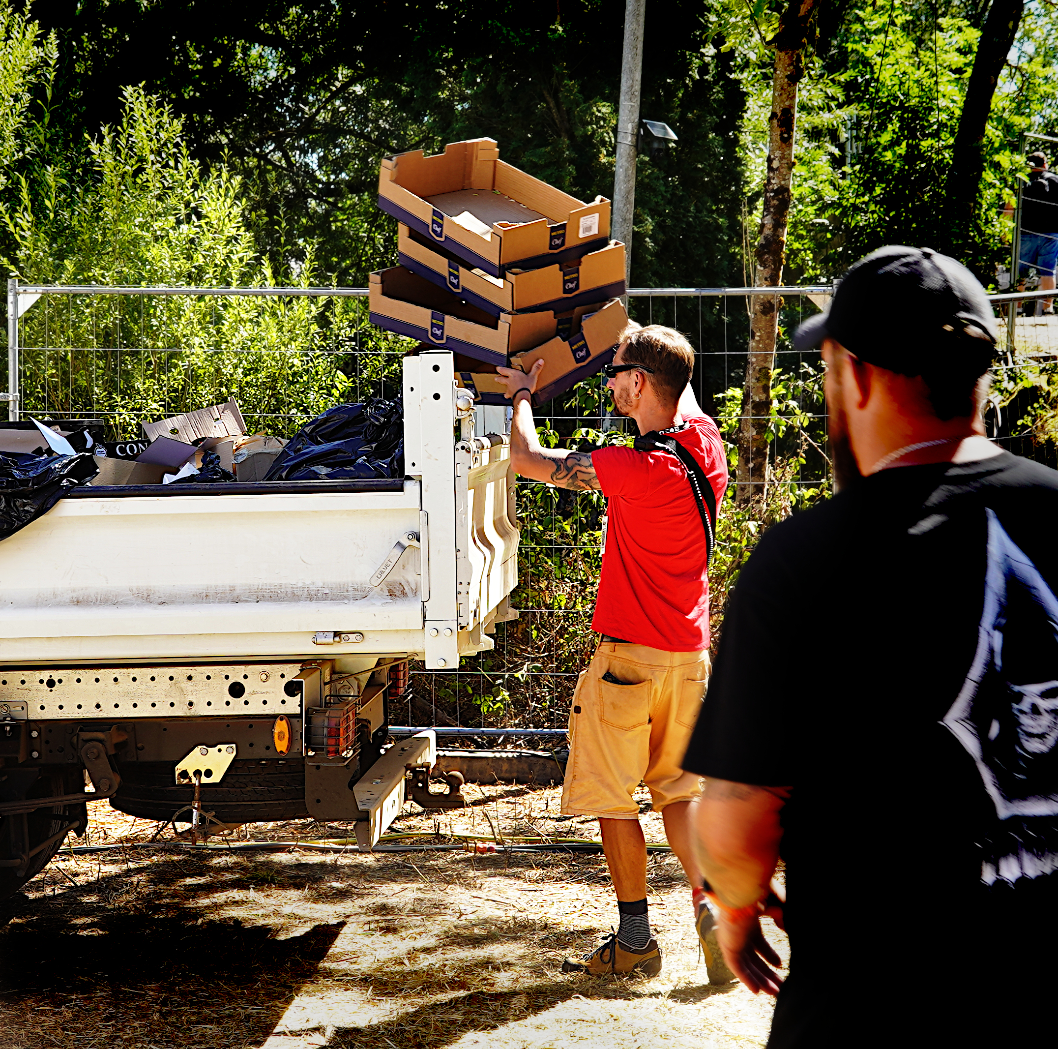 une personne empile des cagettes vides dans la benne du camion utilisaire