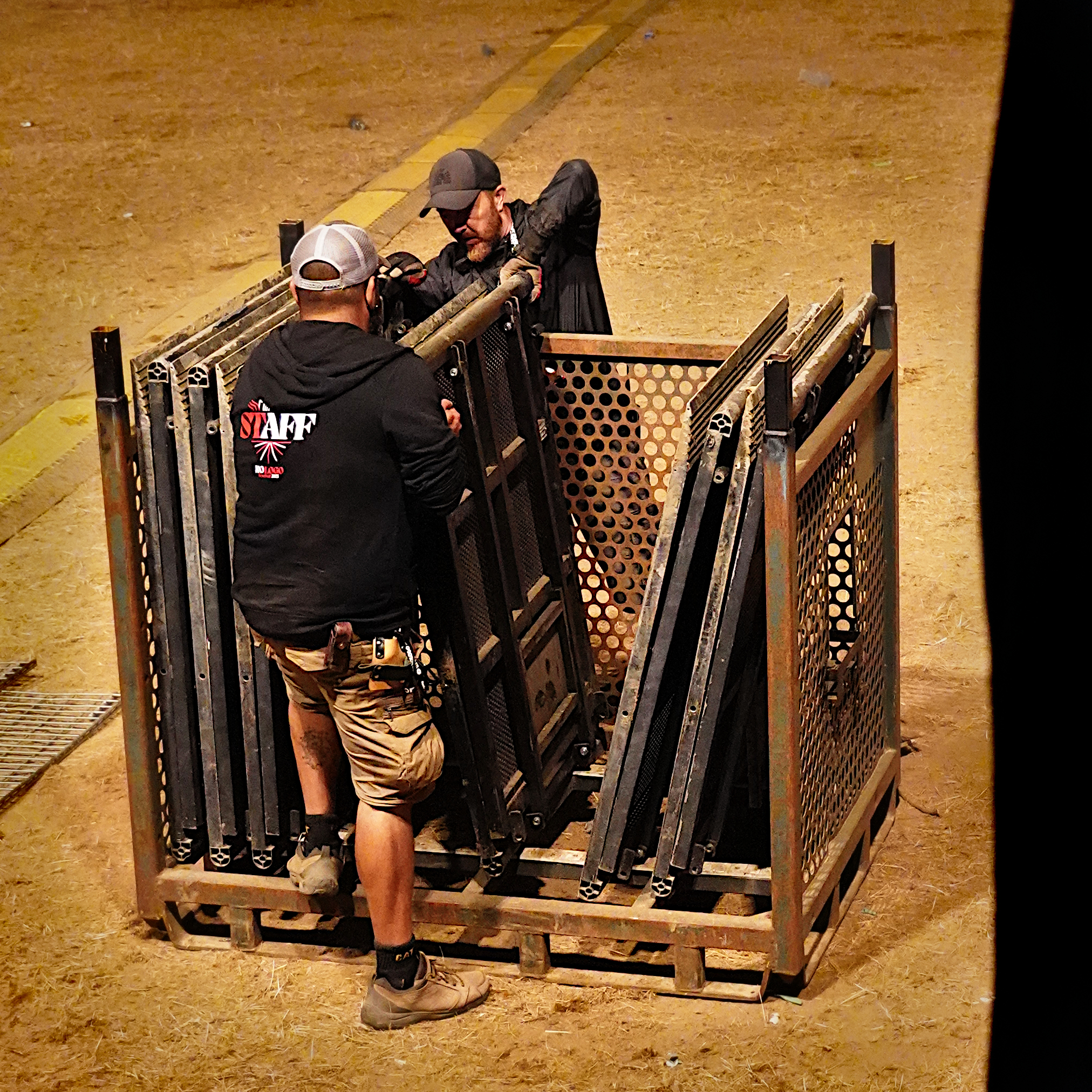 deux personnes du staff sortent des éléments métalliques d'un rack de rangement de la scène